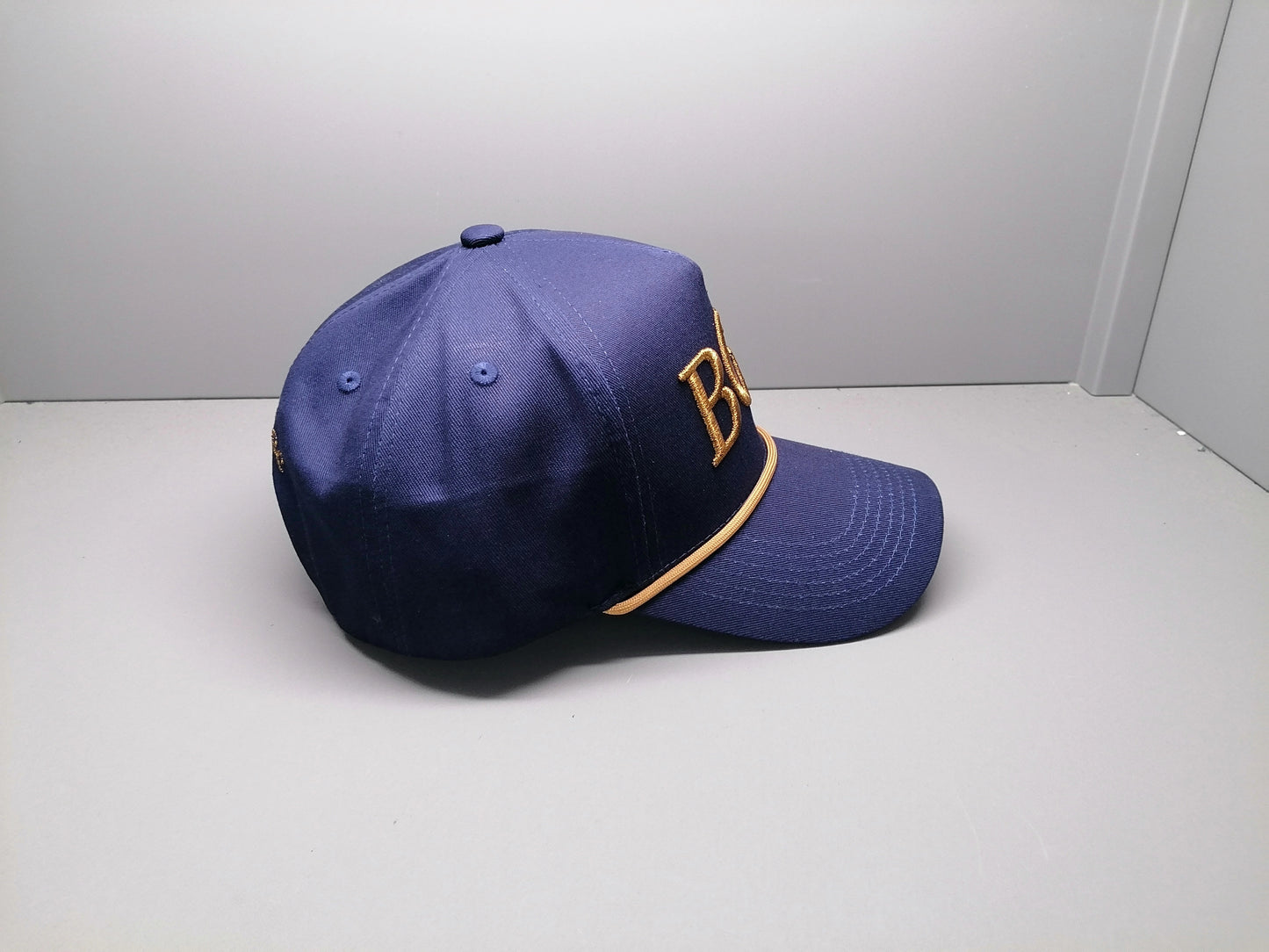 Side profile of The Major premium golf rope cap showing structured five-panel construction and braided rope
