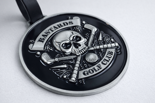 Metallic pendant with skull design and golf club elements on a white background